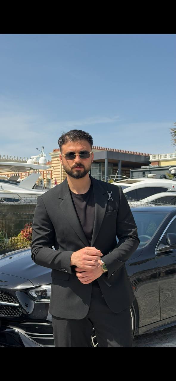 Men’s black slim fit suit with structured tailoring and harness detail, modern formal outfit styled with black shoes and minimal design