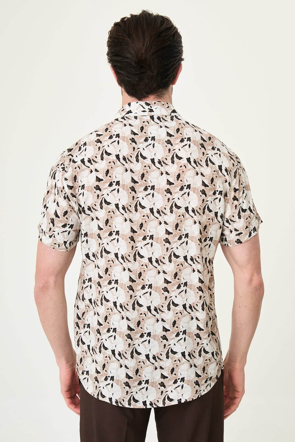 Men wearing a camel-patterned short-sleeved casual shirt, slim fit, standing with one hand in pocket, styled with dark trousers.