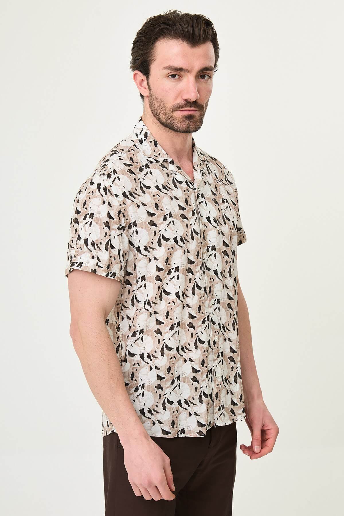 Men wearing a camel-patterned short-sleeved casual shirt, slim fit, standing with one hand in pocket, styled with dark trousers.