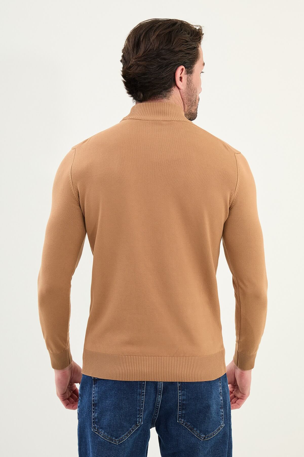 Man wearing a slim fit camel mock neck sweater with ribbed collar, cuffs, and hem.