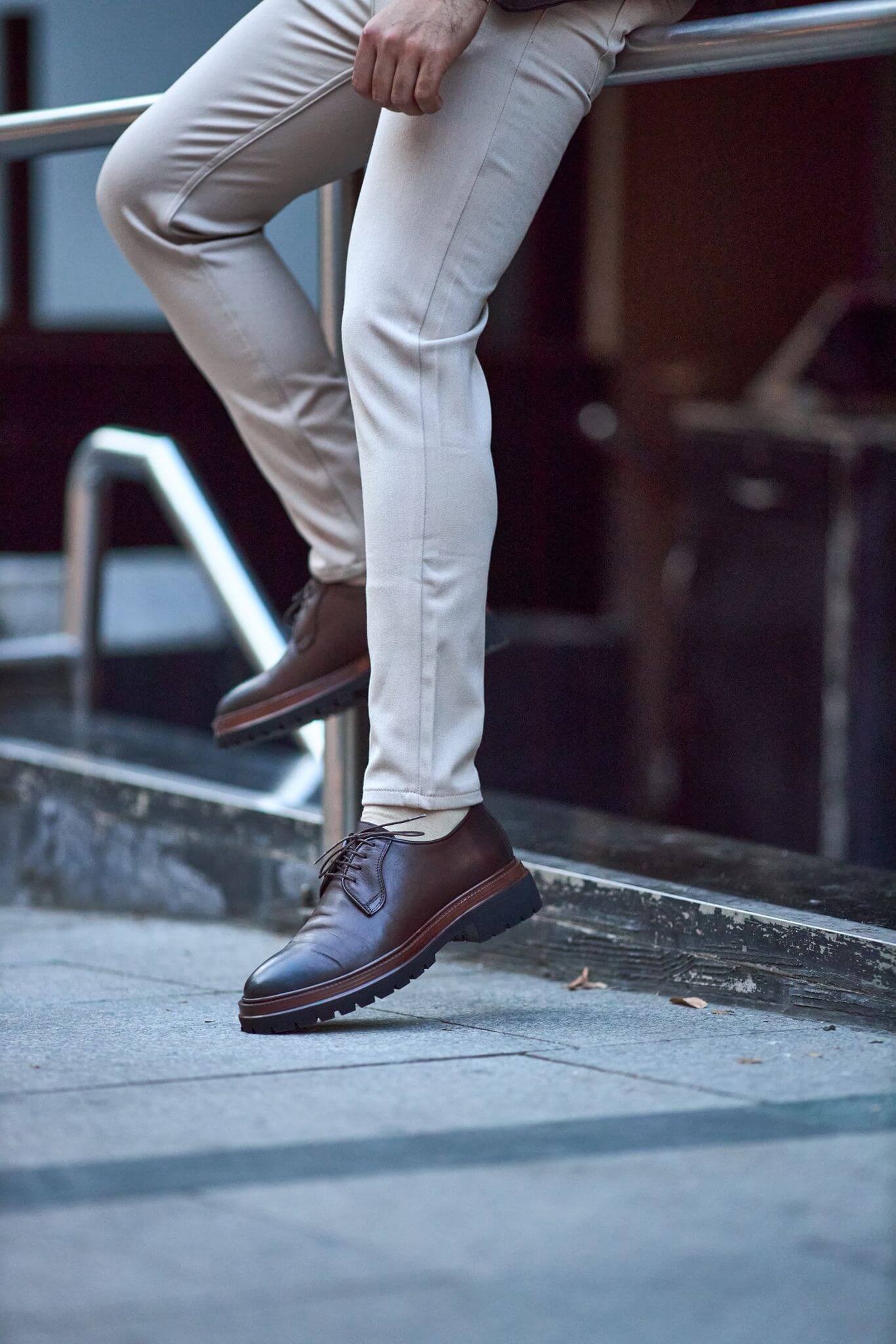 Men’s brown genuine leather chunky Derby shoes worn outdoors on pavement.