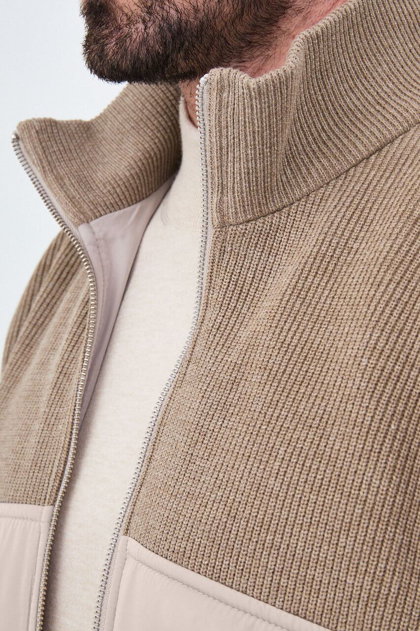 Beige men's casual jacket styled with a cream sweater and dark trousers.
