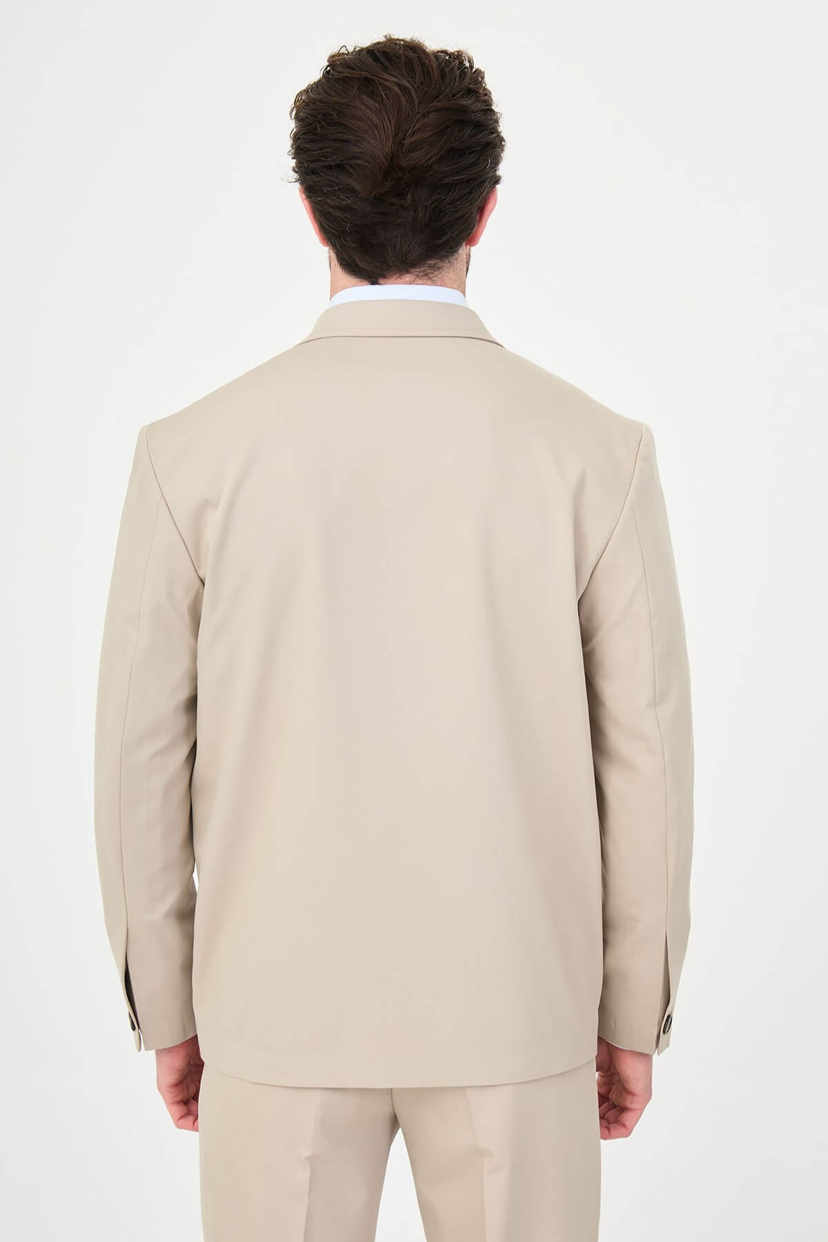 Man wearing a slim fit beige suit with notch lapel, paired with dress shoes.