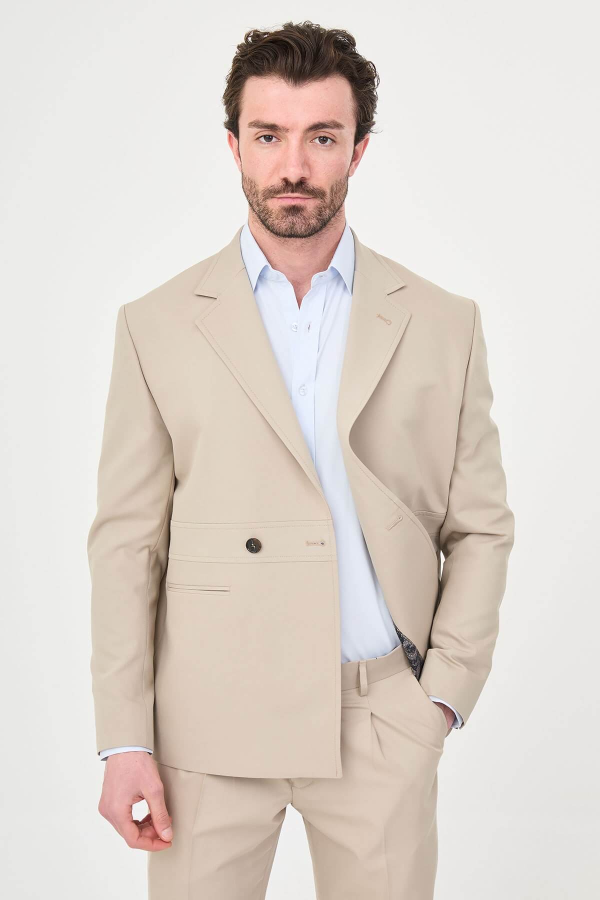Man wearing a slim fit beige suit with notch lapel, paired with dress shoes.