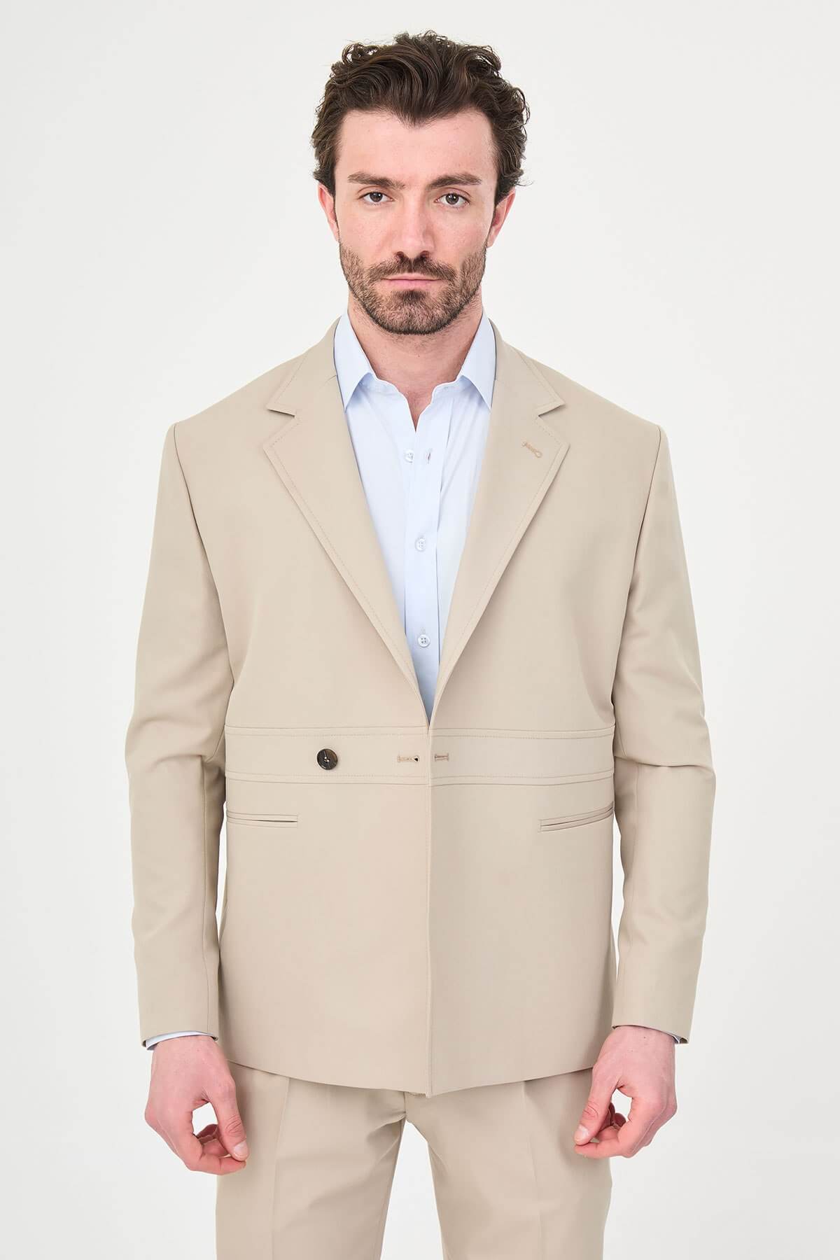Man wearing a slim fit beige suit with notch lapel, paired with dress shoes.