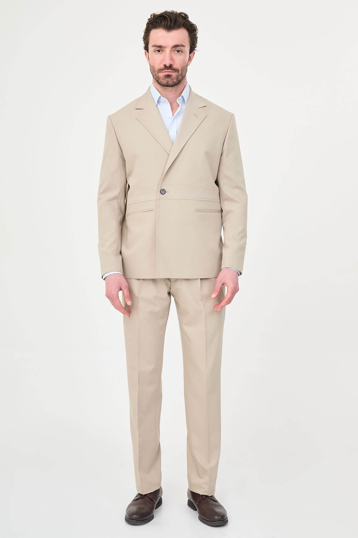 Man wearing a slim fit beige suit with notch lapel, paired with dress shoes.