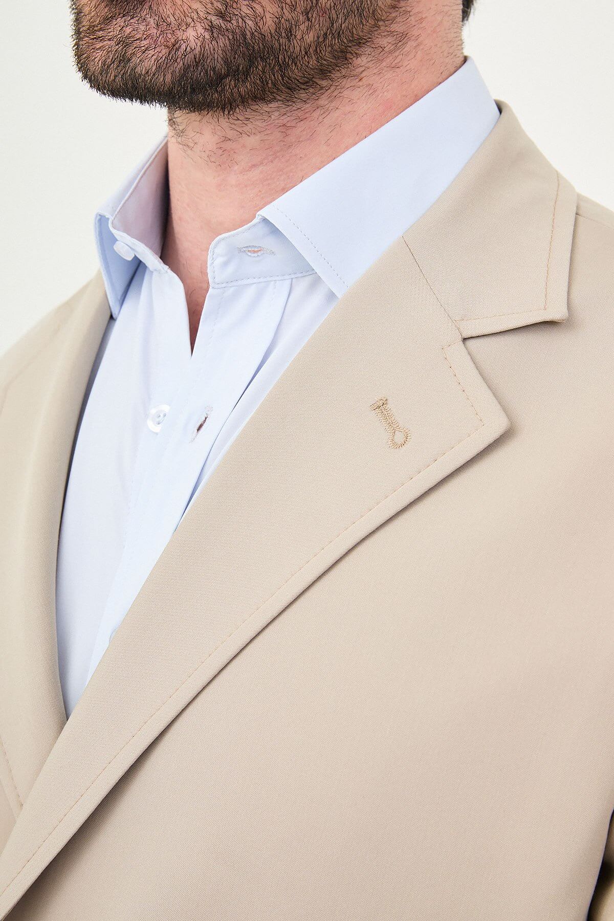 Man wearing a slim fit beige suit with notch lapel, paired with dress shoes.