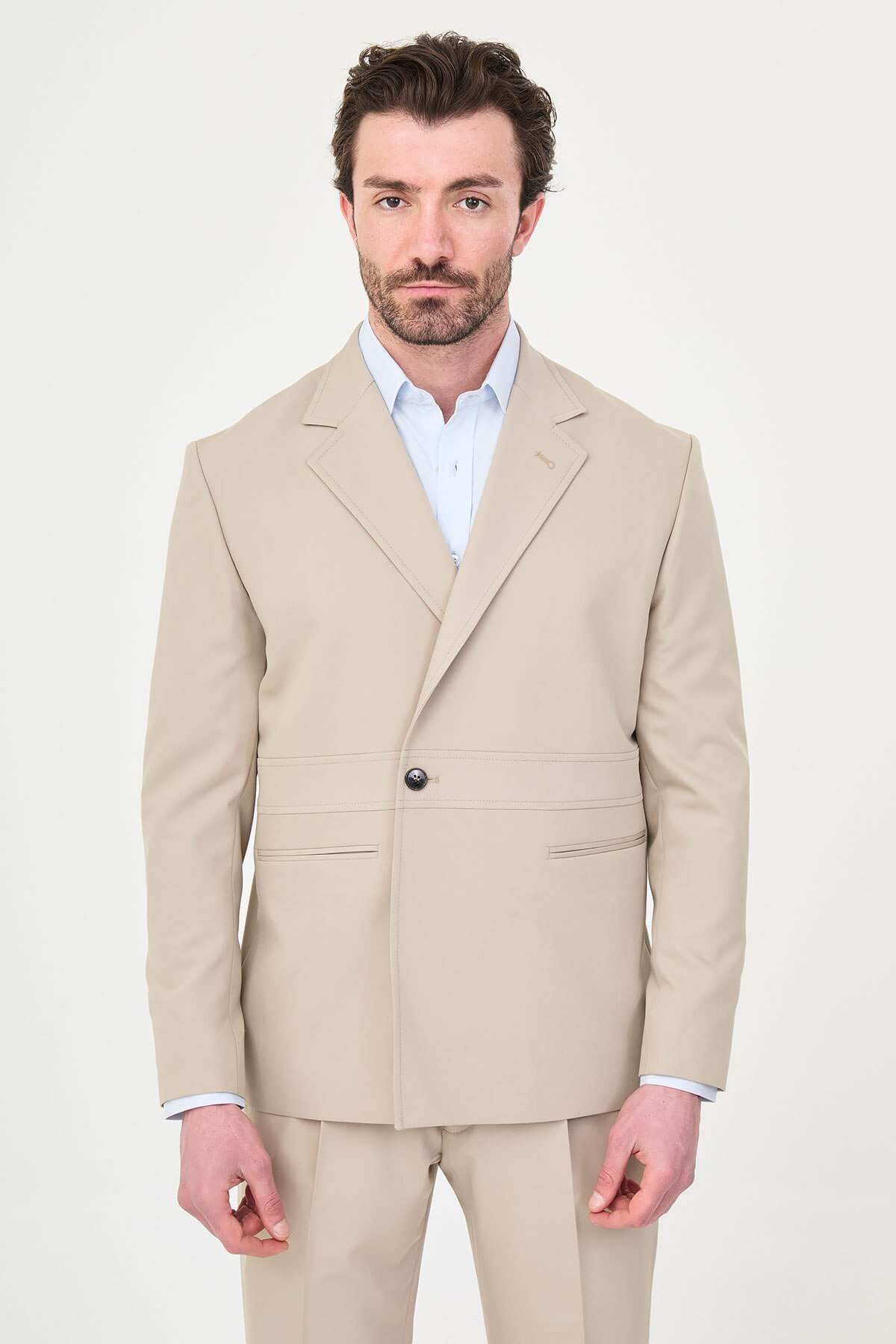 Man wearing a slim fit beige suit with notch lapel, paired with dress shoes.