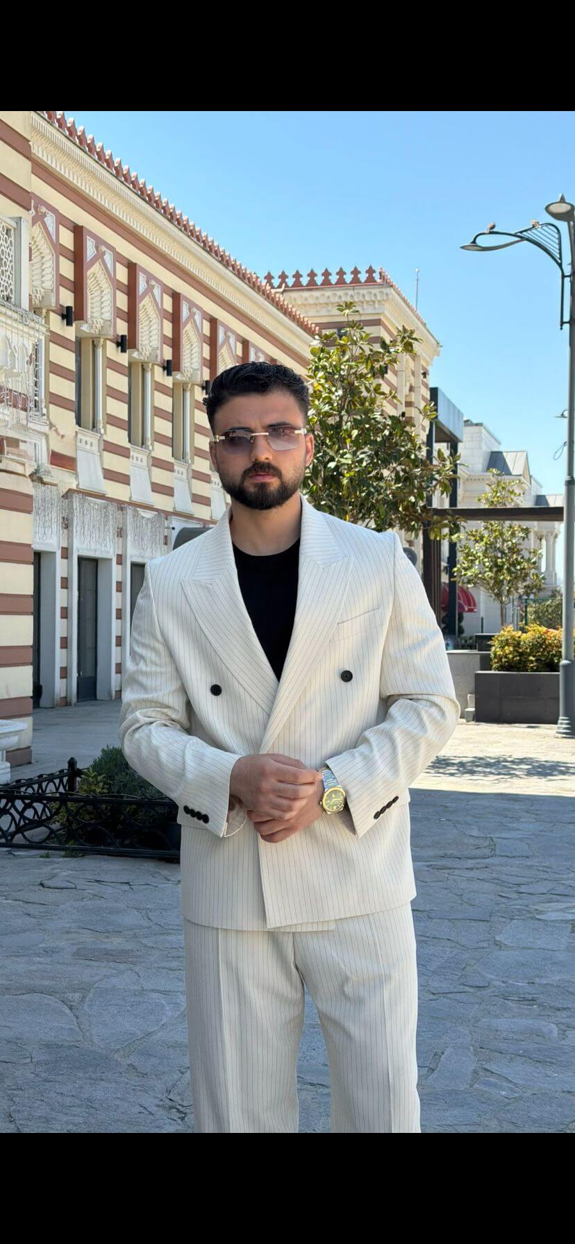 Men wearing beige shawl lapel slim-fit suit with matching trousers, styled outdoors, front view.