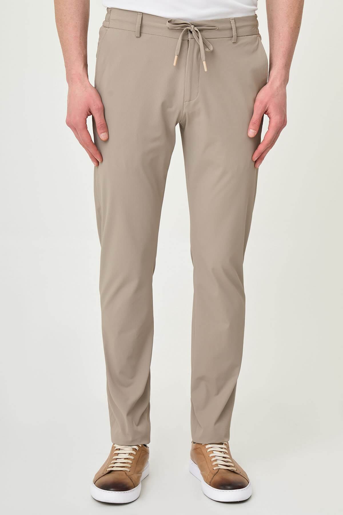 Man wearing beige slim-fit summer trousers styled with white sneakers and a white polo shirt.