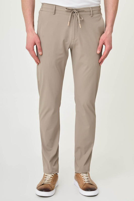 Man wearing beige slim-fit summer trousers styled with white sneakers and a white polo shirt.