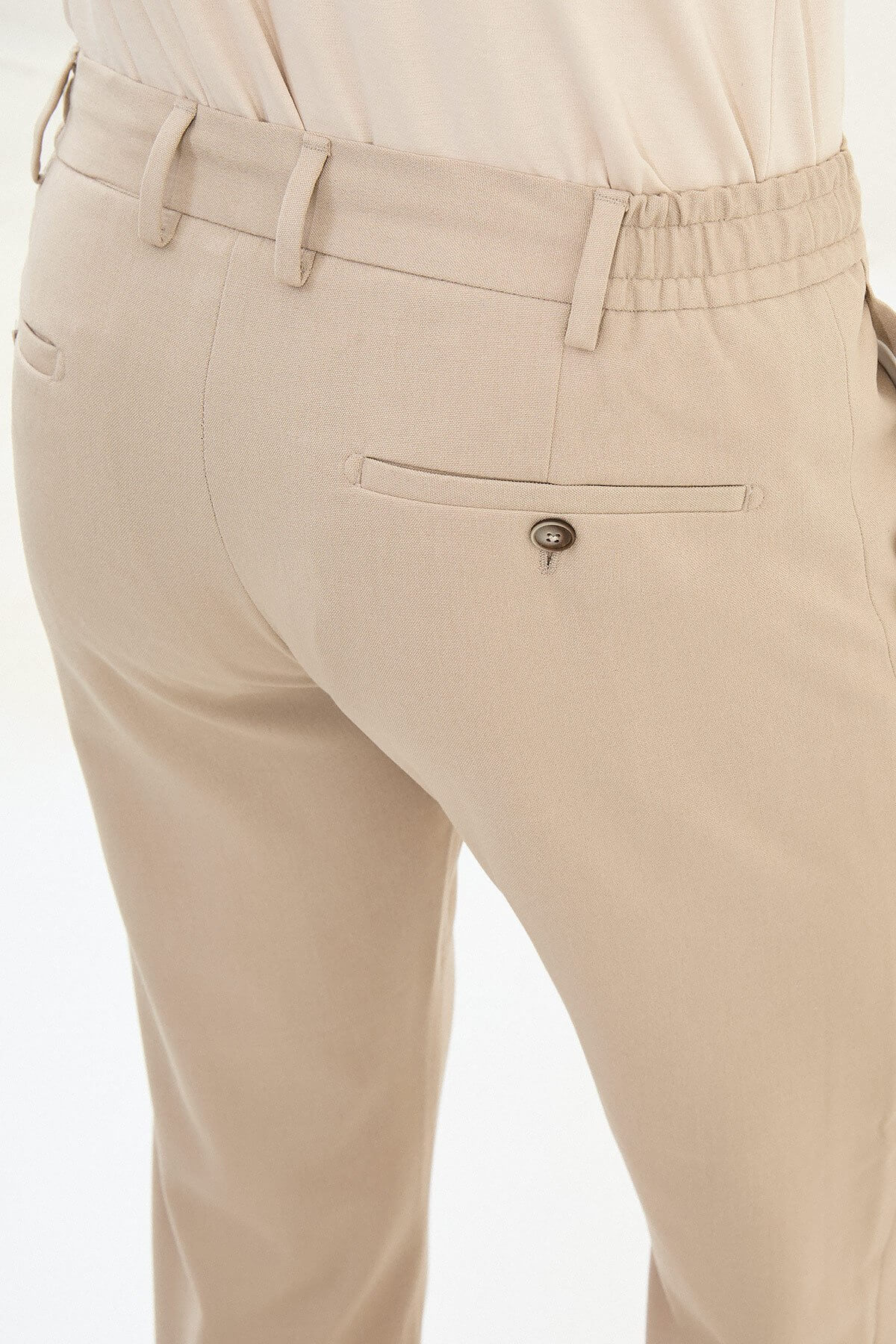 Man wearing beige slim-fit drawstring trousers with elastic waistband, styled with loafers and a summer shirt for versatile summer menswear.