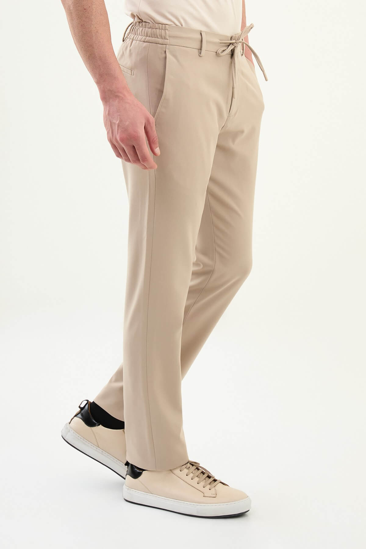Man wearing beige slim-fit drawstring trousers with elastic waistband, styled with loafers and a summer shirt for versatile summer menswear.