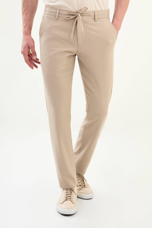 Man wearing beige slim-fit drawstring trousers with elastic waistband, styled with loafers and a summer shirt for versatile summer menswear.
