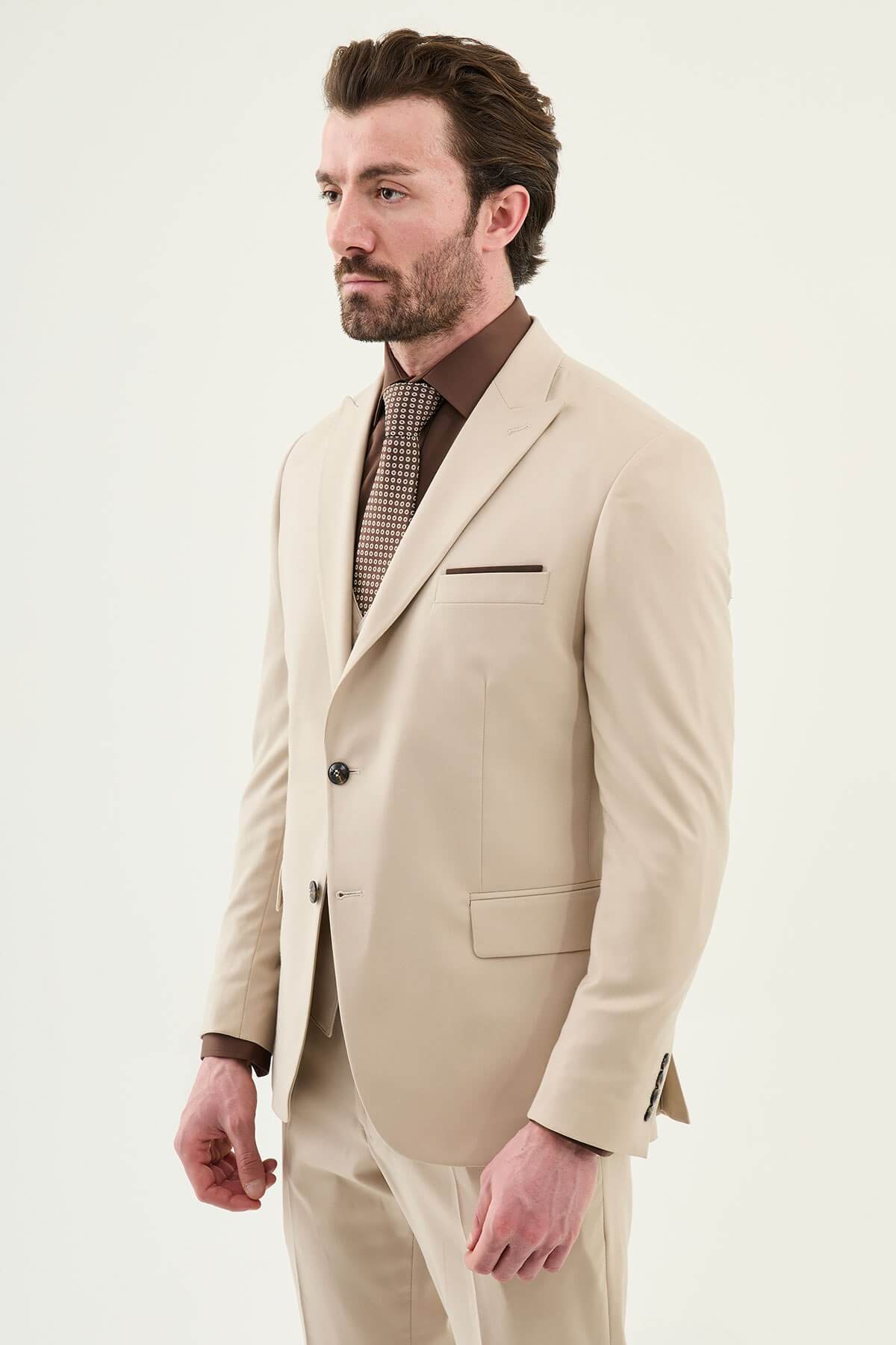Beige slim-fit three-piece men’s suit with brown shirt and patterned tie