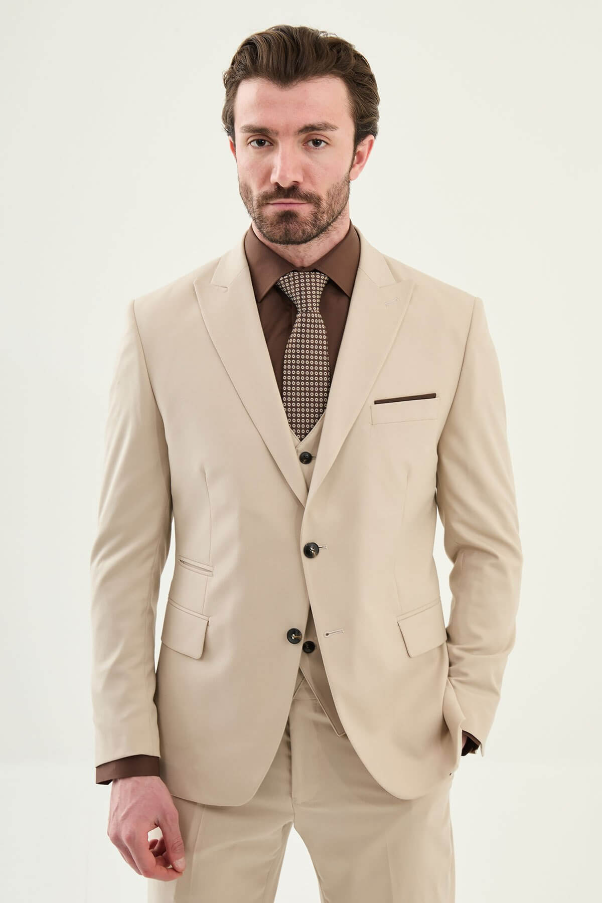 Beige slim-fit three-piece men’s suit with brown shirt and patterned tie