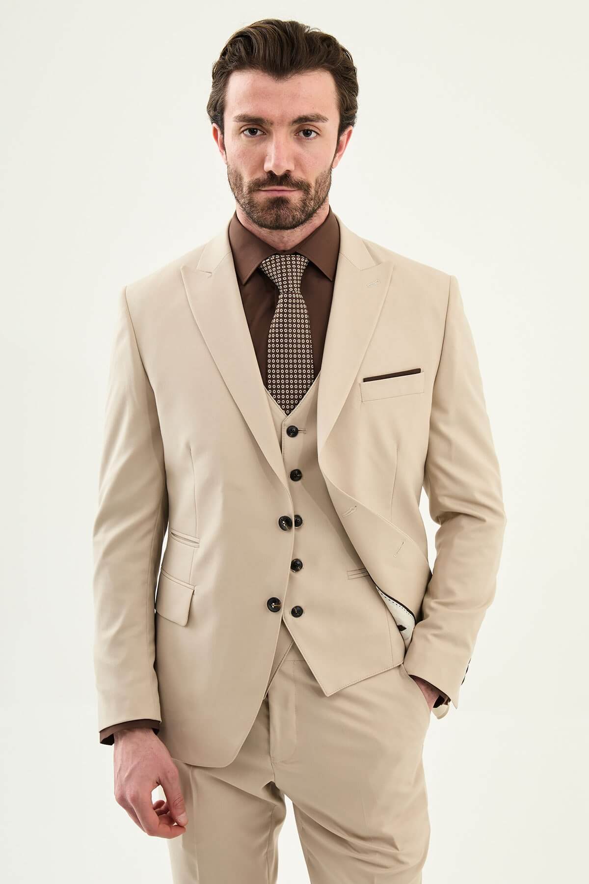 Beige slim-fit three-piece men’s suit with brown shirt and patterned tie