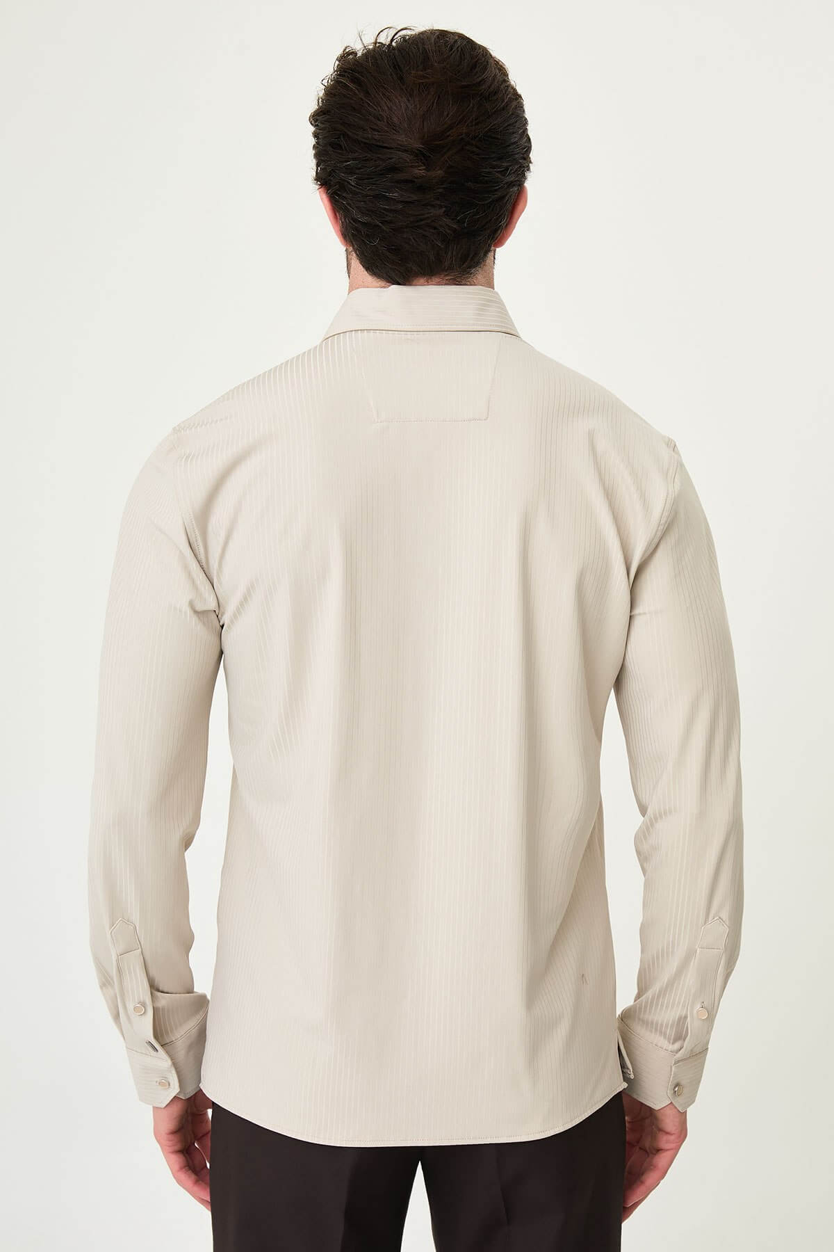 Beige slim-fit long sleeve men’s shirt with subtle stripes, worn with dark trousers, front view.