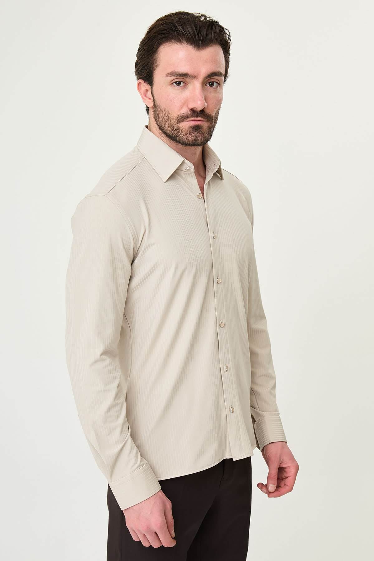 Beige slim-fit long sleeve men’s shirt with subtle stripes, worn with dark trousers, front view.