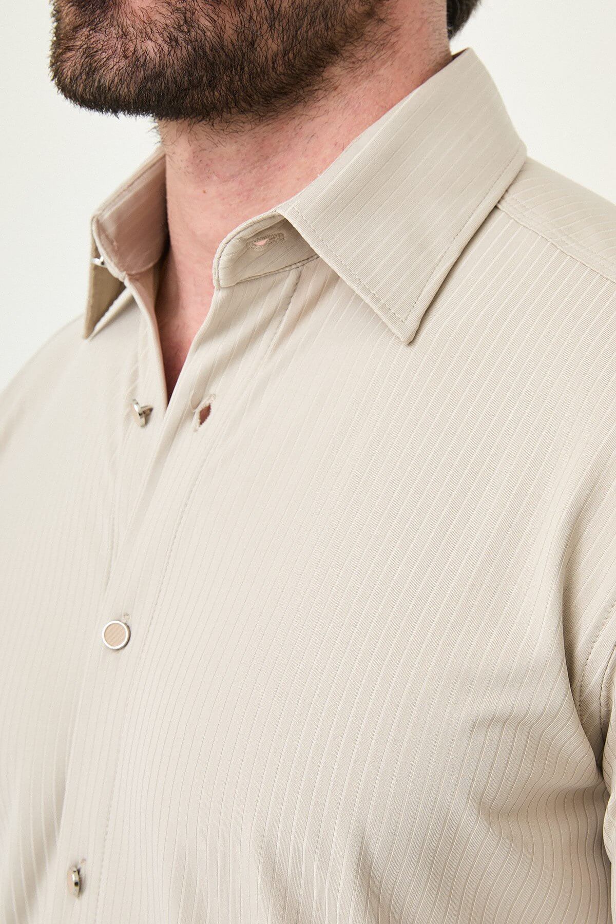 Beige slim-fit long sleeve men’s shirt with subtle stripes, worn with dark trousers, front view.