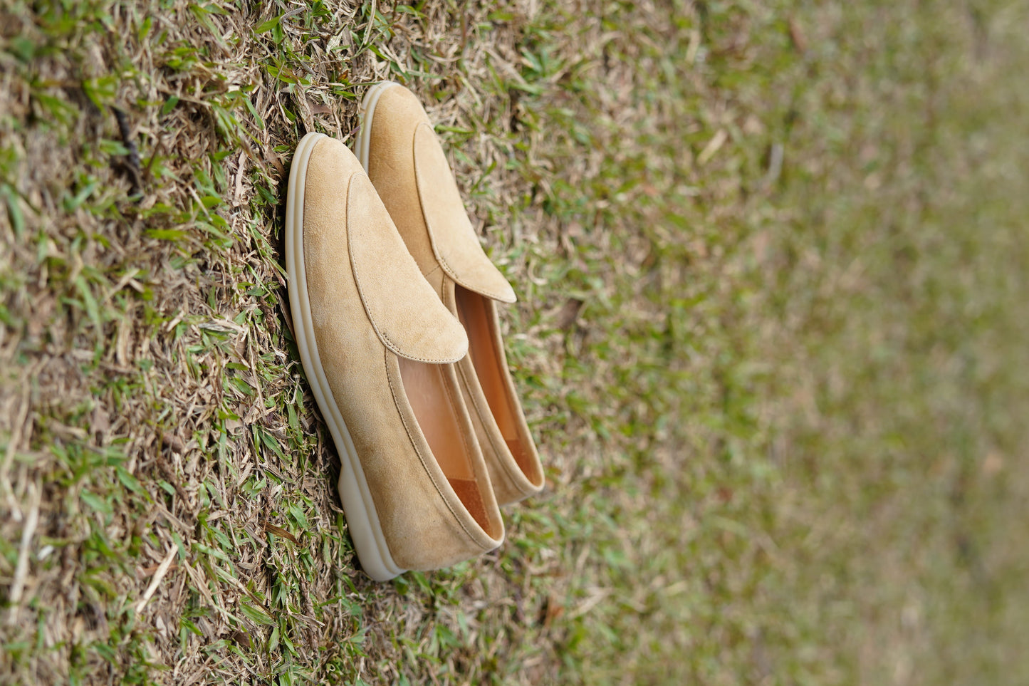 Men’s beige suede slip-on loafers featuring a minimalist apron vamp design and lightweight cream sole, perfect for smart-casual summer outfits.