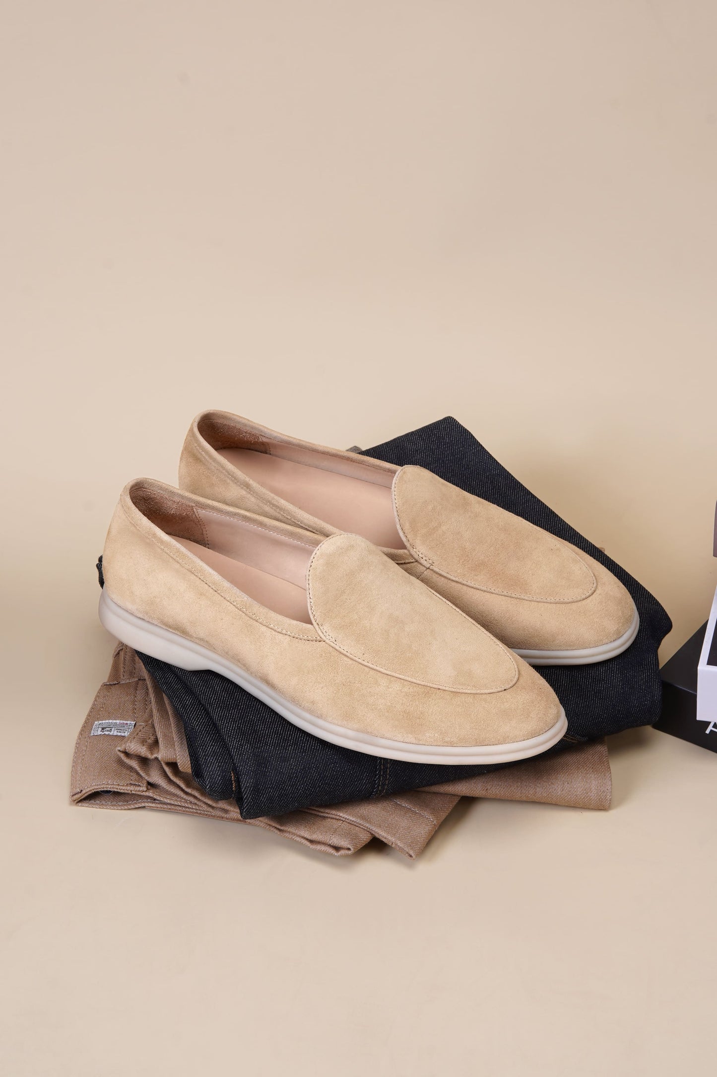 Men’s beige suede slip-on loafers featuring a minimalist apron vamp design and lightweight cream sole, perfect for smart-casual summer outfits.