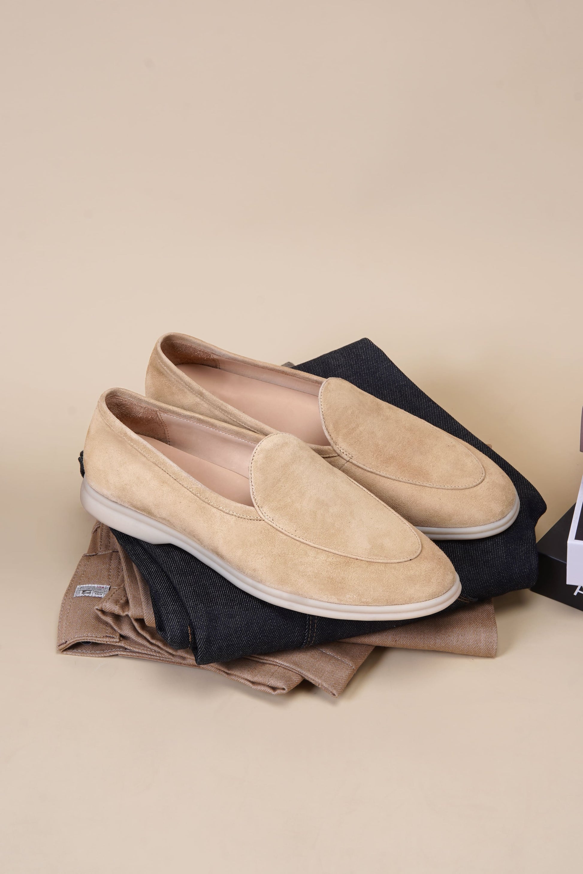 Men’s beige suede slip-on loafers featuring a minimalist apron vamp design and lightweight cream sole, perfect for smart-casual summer outfits.