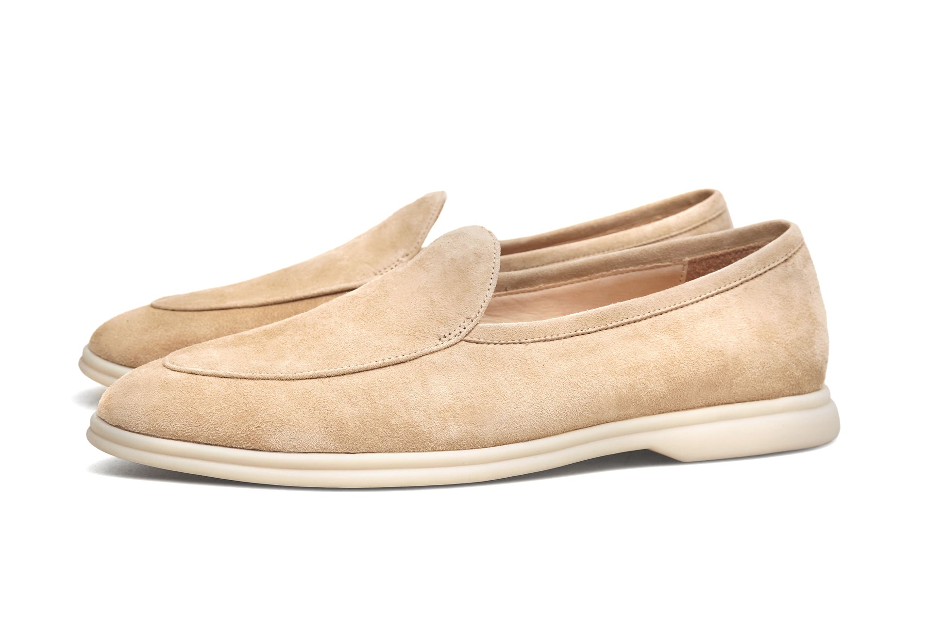 Men’s beige suede slip-on loafers featuring a minimalist apron vamp design and lightweight cream sole, perfect for smart-casual summer outfits.