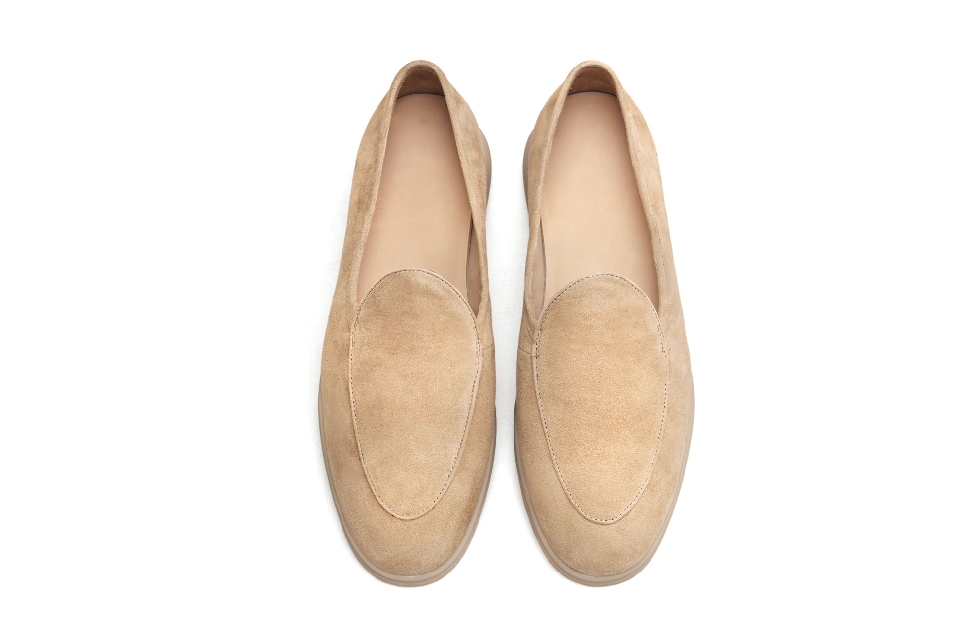 Men’s beige suede slip-on loafers featuring a minimalist apron vamp design and lightweight cream sole, perfect for smart-casual summer outfits.
