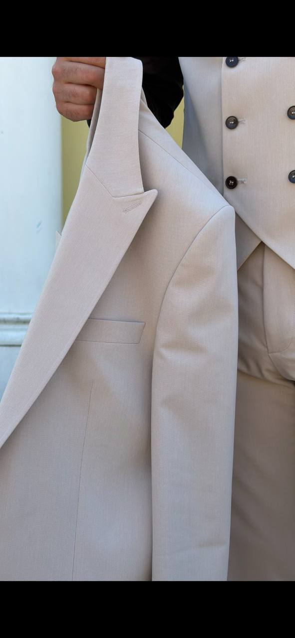 beige three-piece slim-fit suit showing the tailored jacket and waistcoat details with black shirt, highlighting the fabric texture and fit.