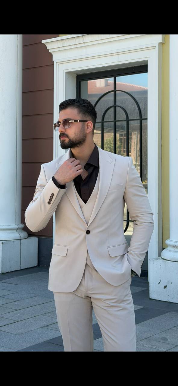 beige three-piece slim-fit suit showing the tailored jacket and waistcoat details with black shirt, highlighting the fabric texture and fit.