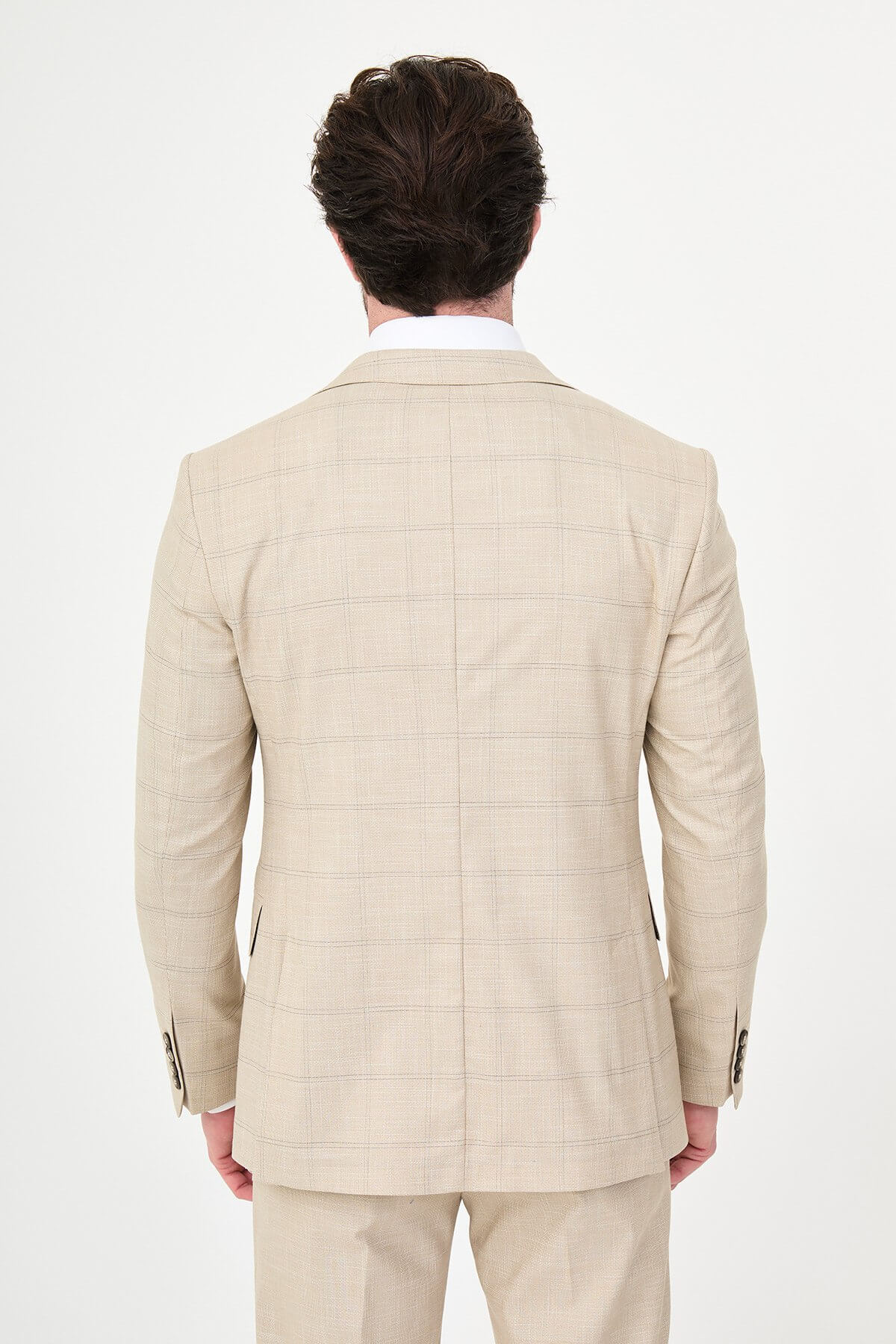 a beige check slim-fit three-piece suit with matching waistcoat and trousers, white dress shirt, patterned navy and brown tie, and dark brown leather shoes.