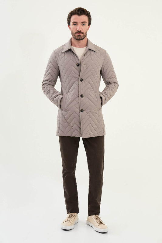 Men’s beige slim fit quilted coat with chevron stitching, styled with brown trousers and sneakers.