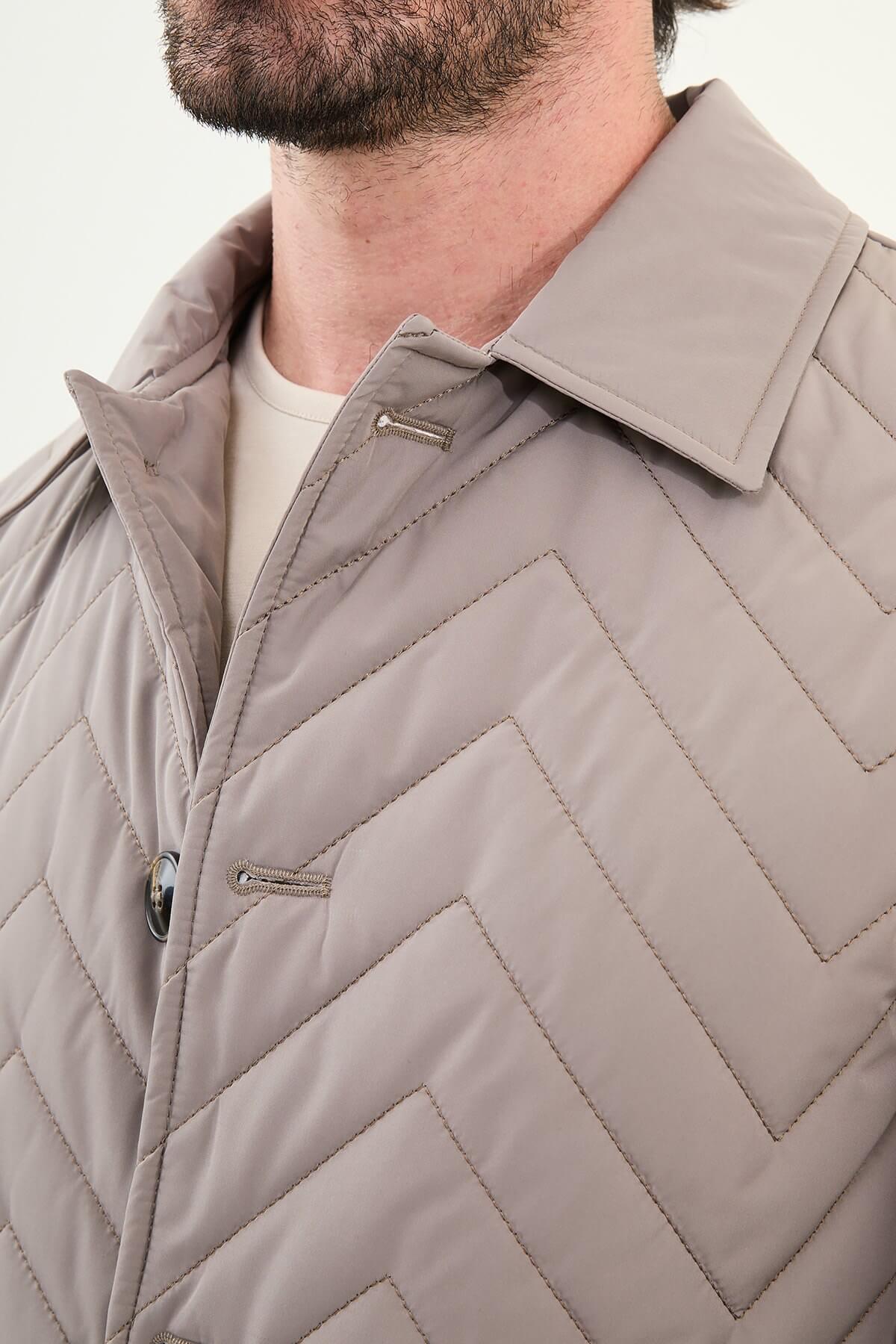 Men’s beige slim fit quilted coat with chevron stitching, styled with brown trousers and sneakers.