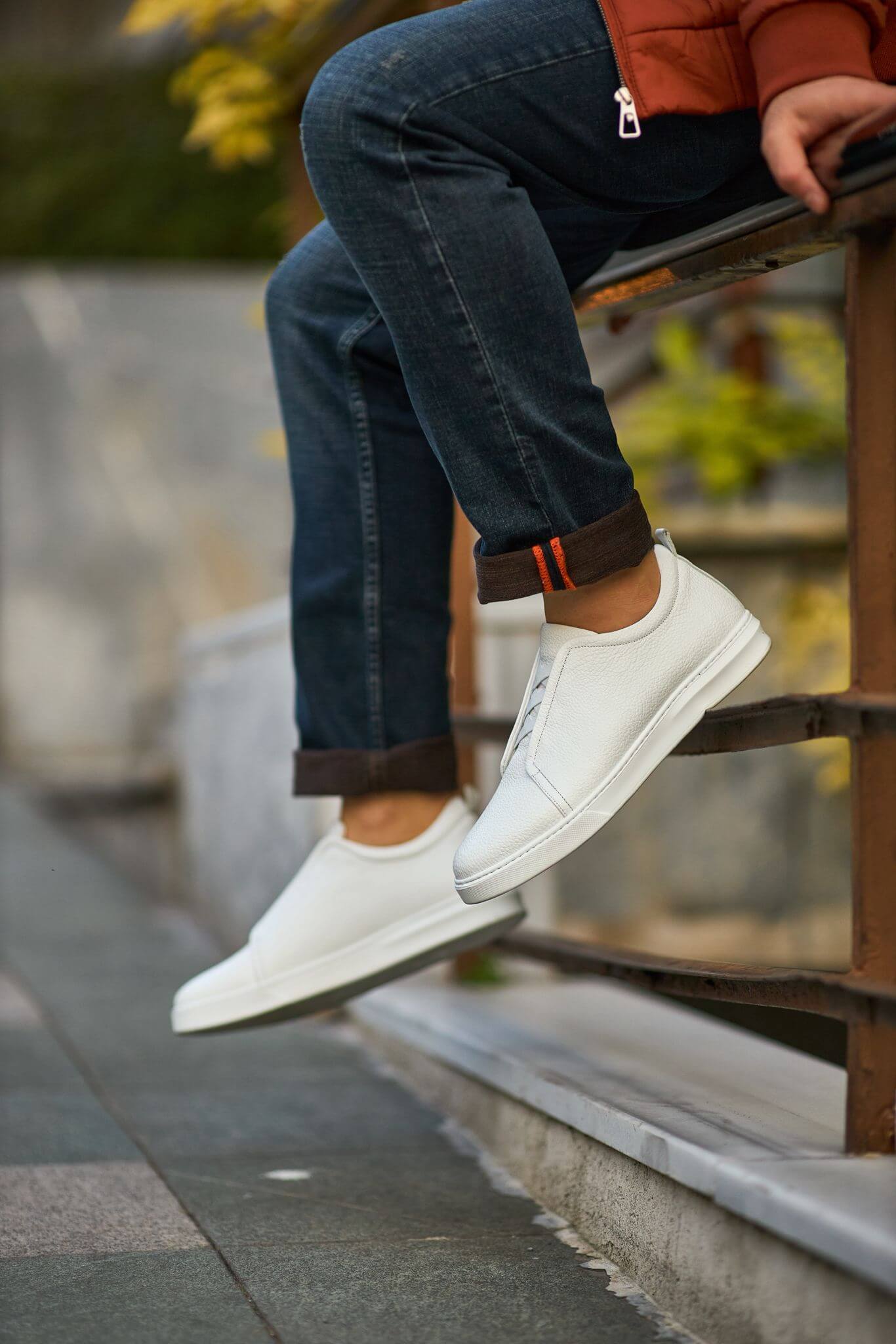 Men’s white leather minimalist court sneaker styled with cuffed denim — premium casual footwear.