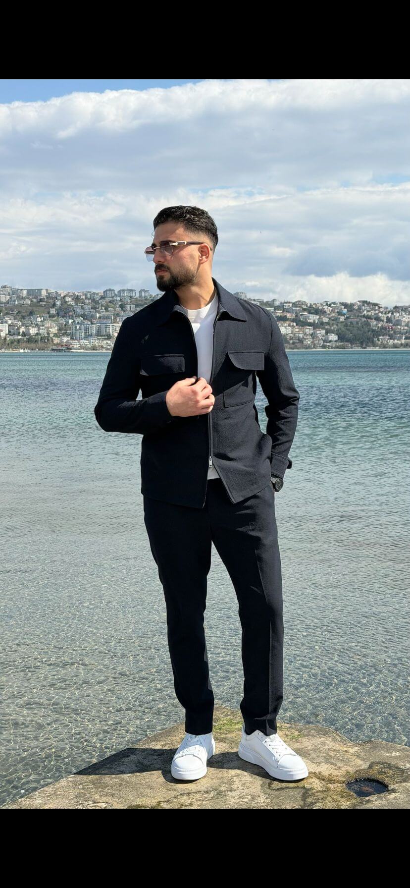 Men’s navy blue cargo co-set featuring a cargo shacket with multiple pockets and matching tracksuit pants, worn outdoors with white sneakers, showcasing a relaxed look.