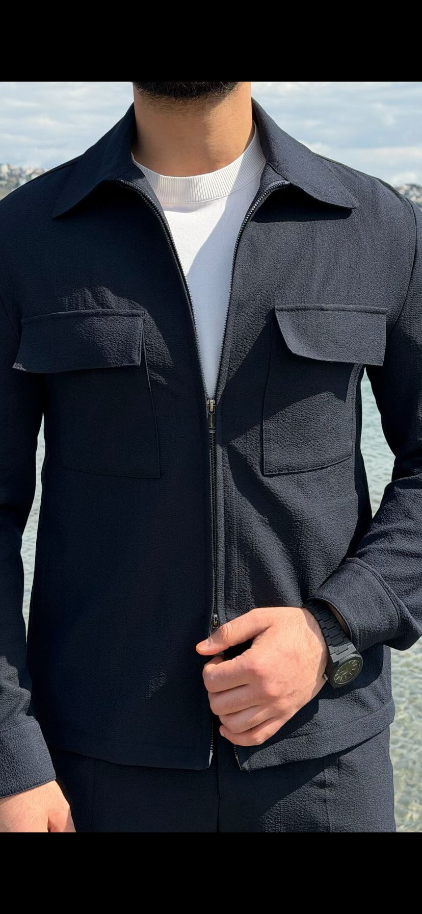 Men’s navy blue cargo co-set featuring a cargo shacket with multiple pockets and matching tracksuit pants, worn outdoors with white sneakers, showcasing a relaxed look.