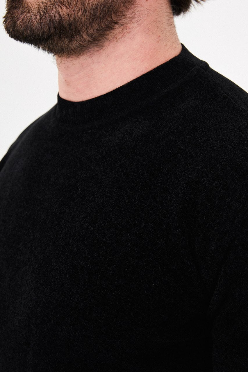 Men’s black crew neck knit sweater in a cotton blend slim fit design styled with grey trousers for a refined fall winter outfit.