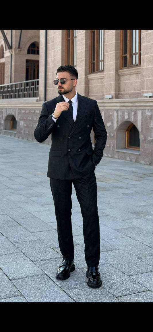 Men’s black double-breasted suit with peak lapel, tailored formal suit styled with white shirt and black tie outdoors