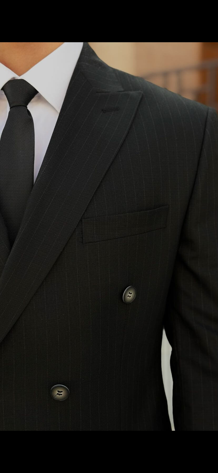 Men’s black double-breasted suit with peak lapel, tailored formal suit styled with white shirt and black tie outdoors