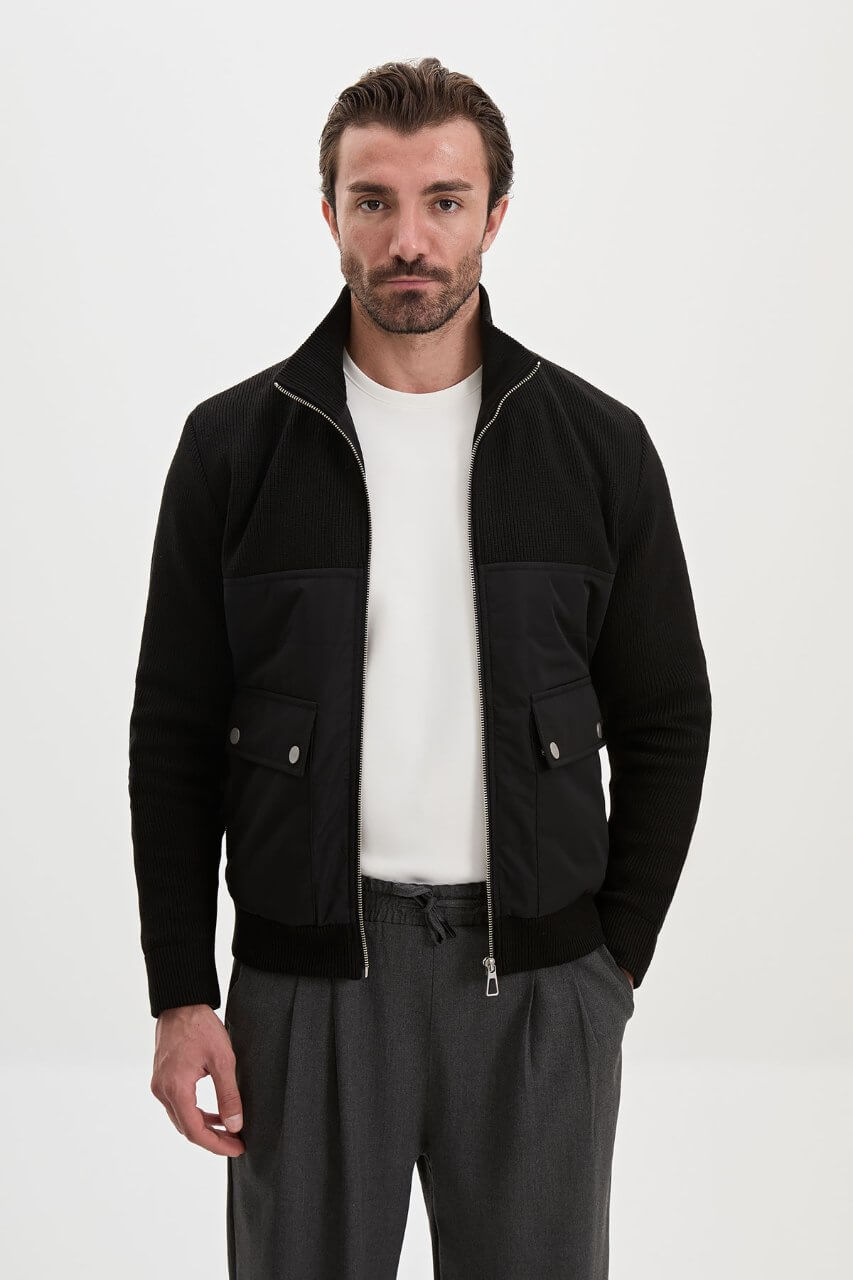 Black men's casual jacket styled with a white T-shirt and grey trousers.