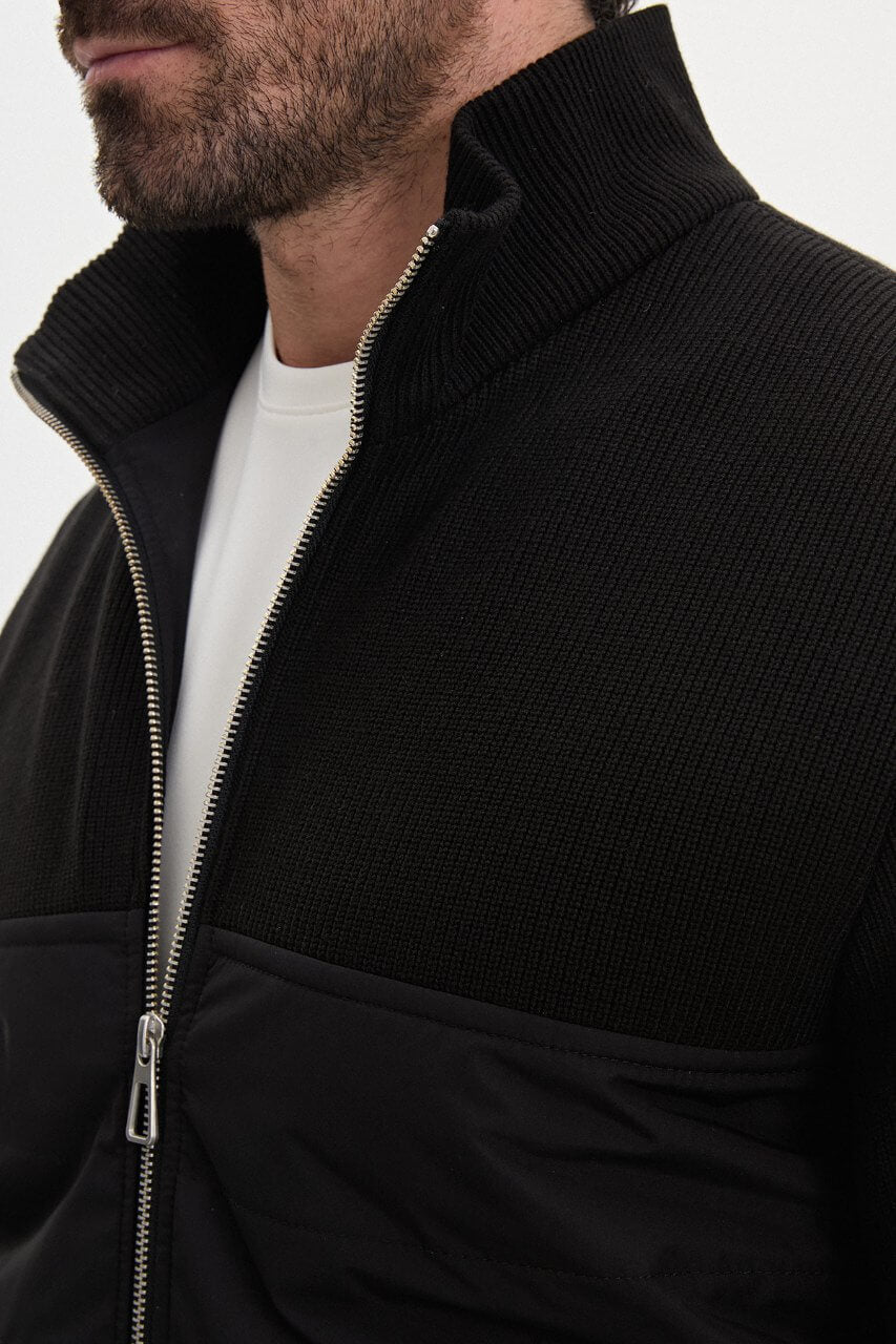 Black men's casual jacket styled with a white T-shirt and grey trousers.
