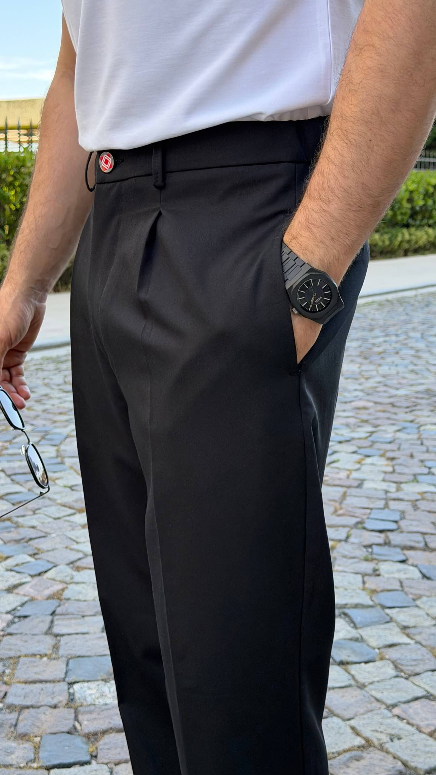 Black pleated trousers showing front pleats and waistband, close-up