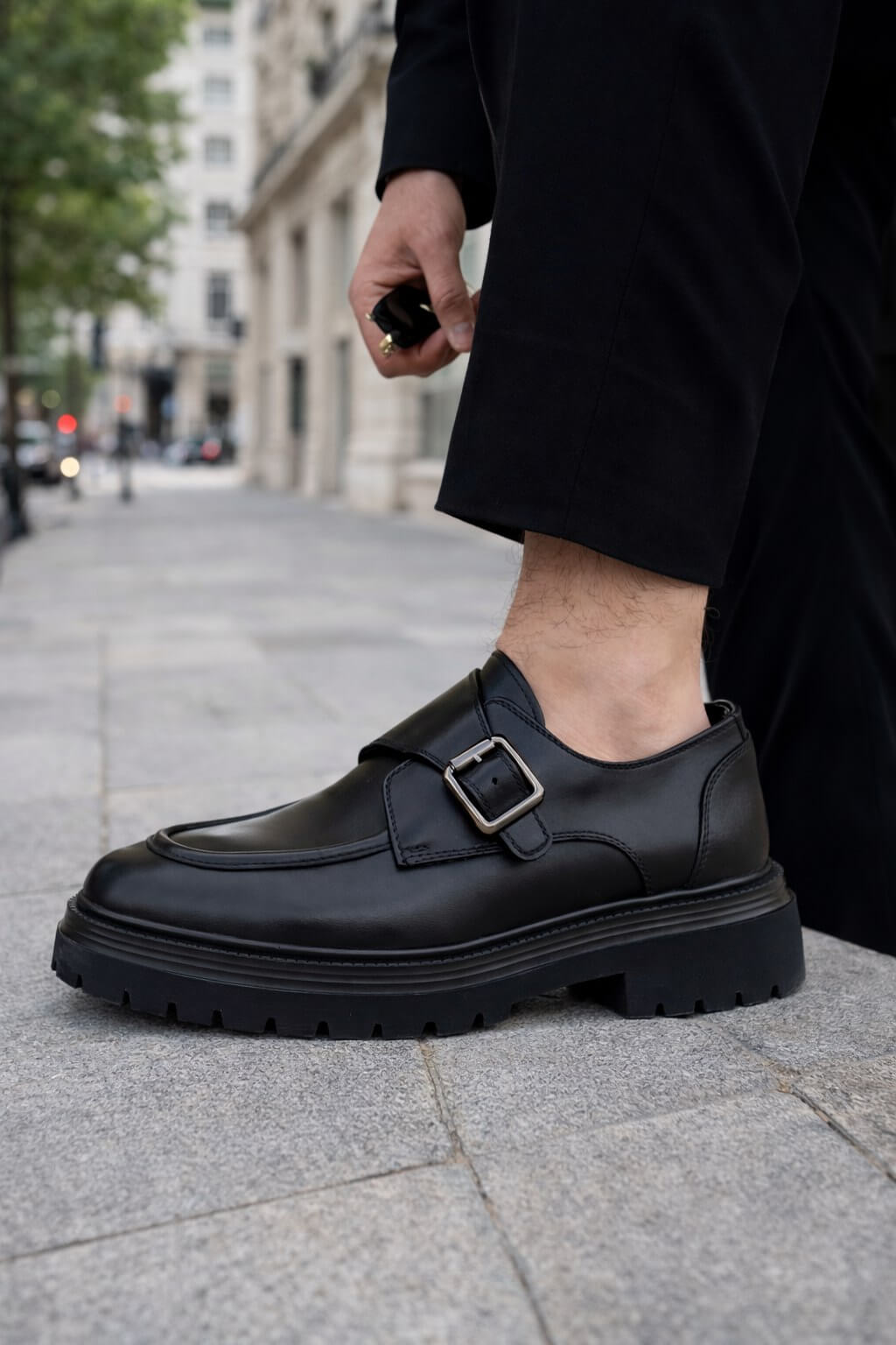 Black leather monk strap shoes with chunky EVA sole on city street