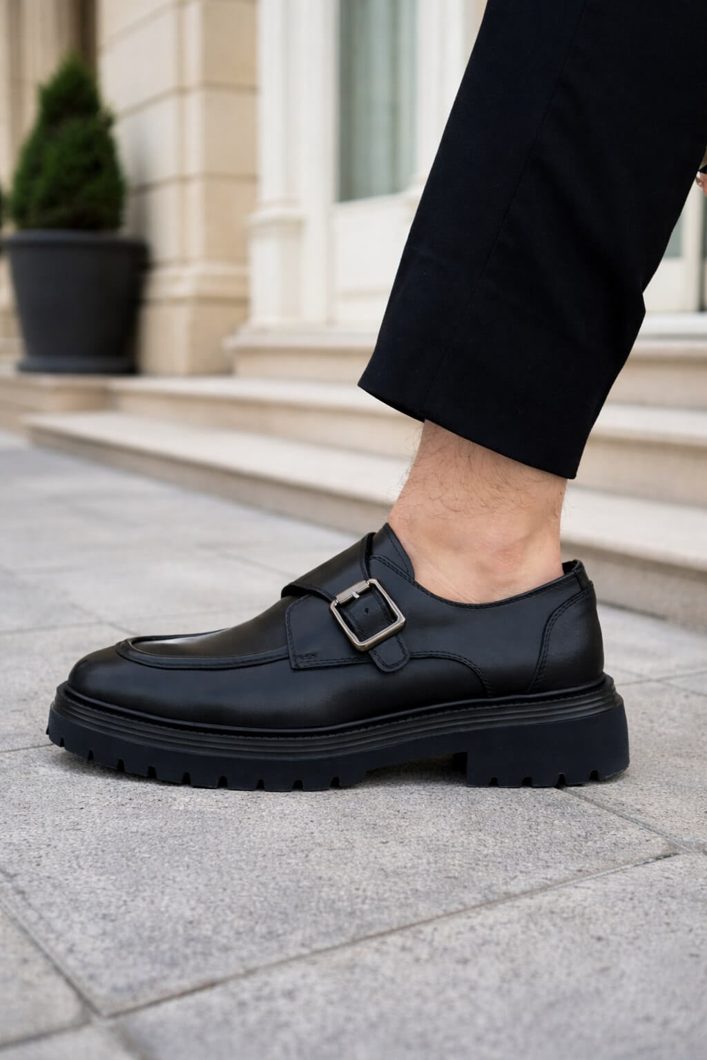 Black leather monk strap shoes with chunky EVA sole on city street