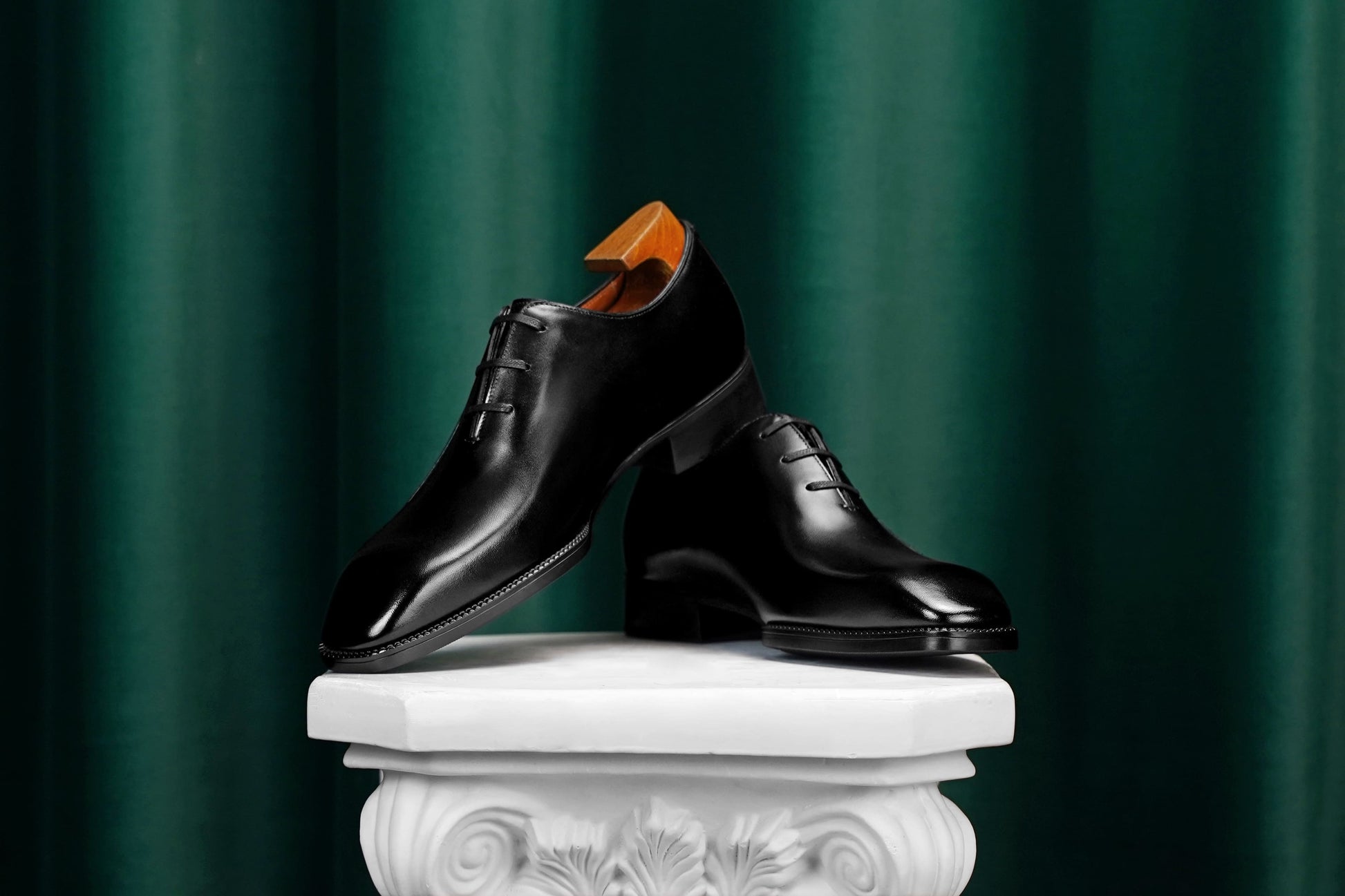 Men’s black leather Oxford dress shoes featuring a polished finish, lace-up closure, sleek pointed toe, and subtle embossed script detailing on the side panel.