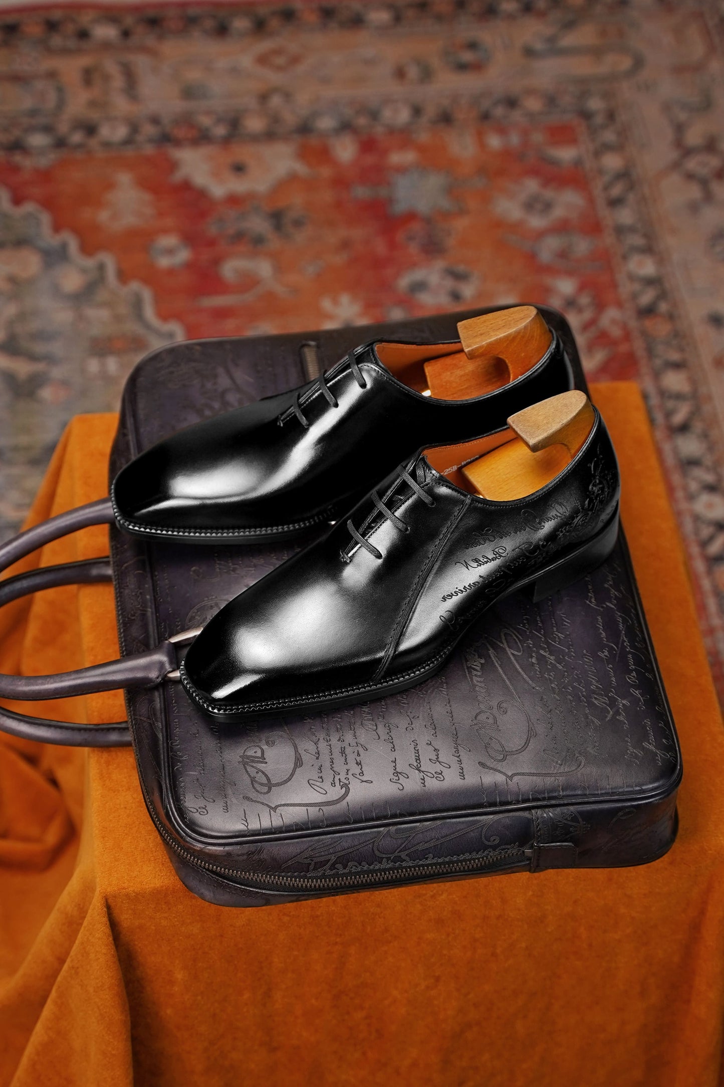 Men’s black leather Oxford dress shoes featuring a polished finish, lace-up closure, sleek pointed toe, and subtle embossed script detailing on the side panel.