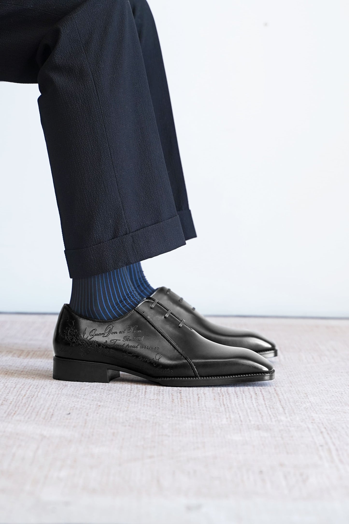 Men’s black leather Oxford dress shoes featuring a polished finish, lace-up closure, sleek pointed toe, and subtle embossed script detailing on the side panel.
