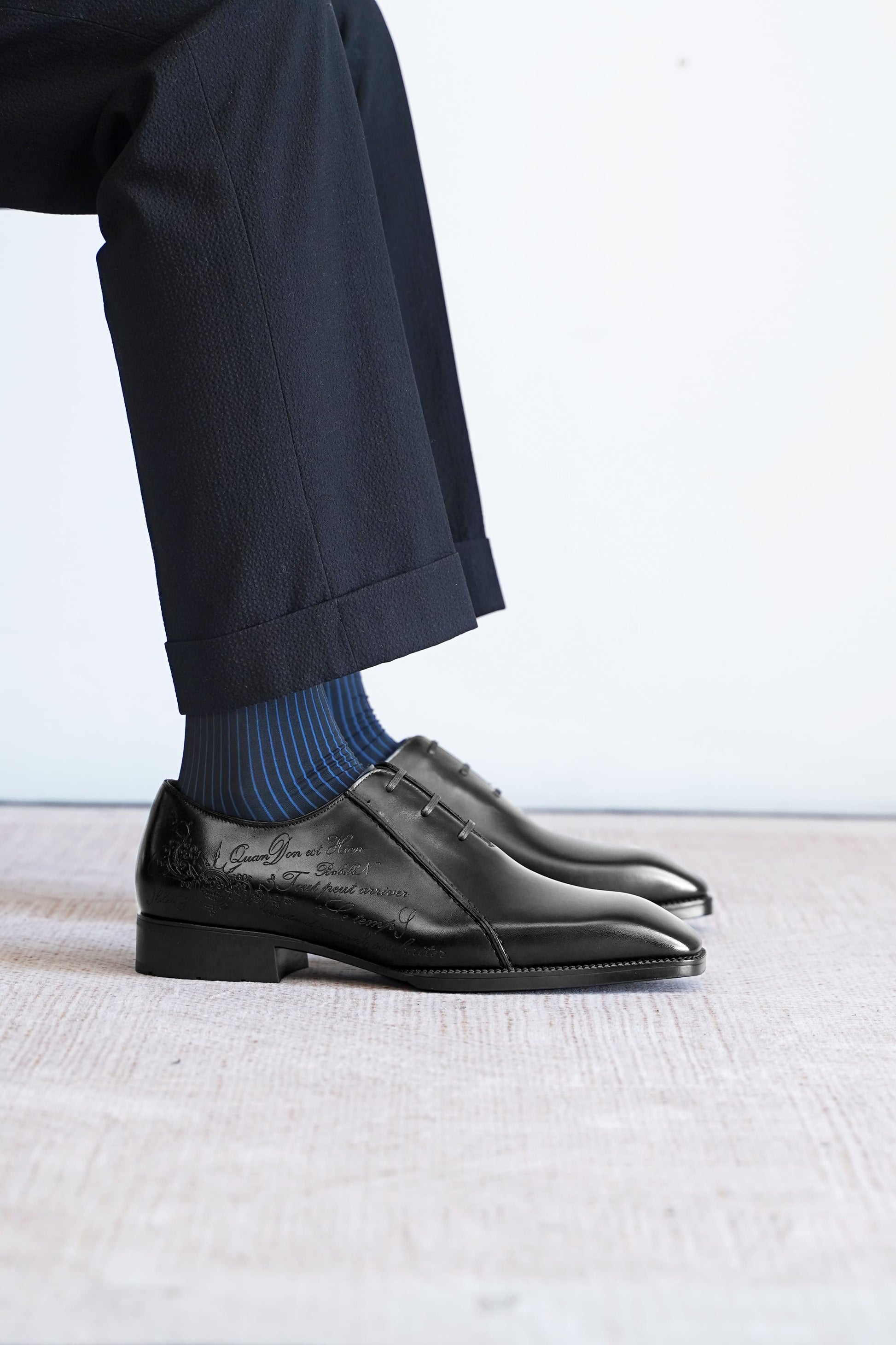 Men’s black leather Oxford dress shoes featuring a polished finish, lace-up closure, sleek pointed toe, and subtle embossed script detailing on the side panel.