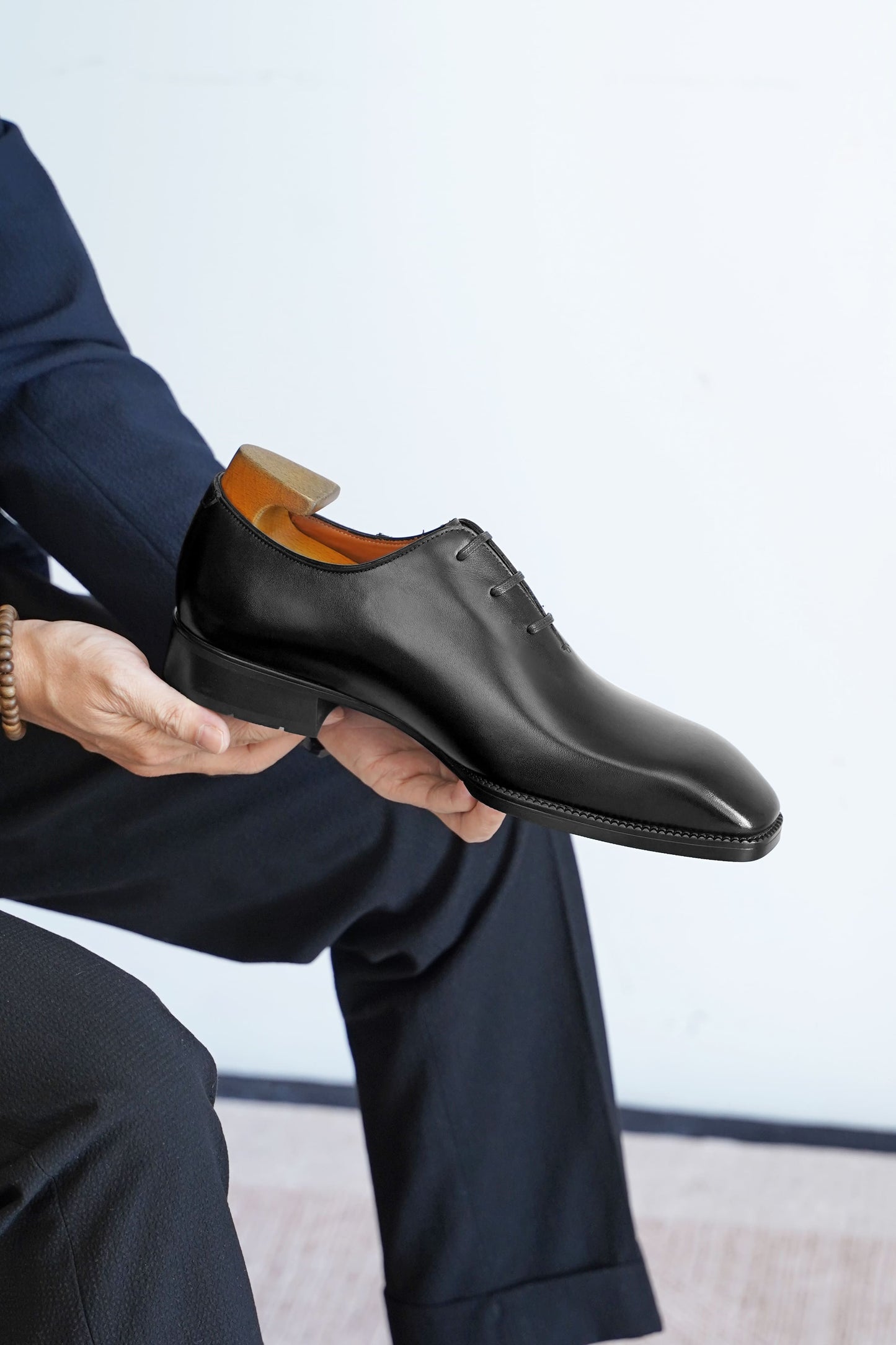 Men’s black leather Oxford dress shoes featuring a polished finish, lace-up closure, sleek pointed toe, and subtle embossed script detailing on the side panel.